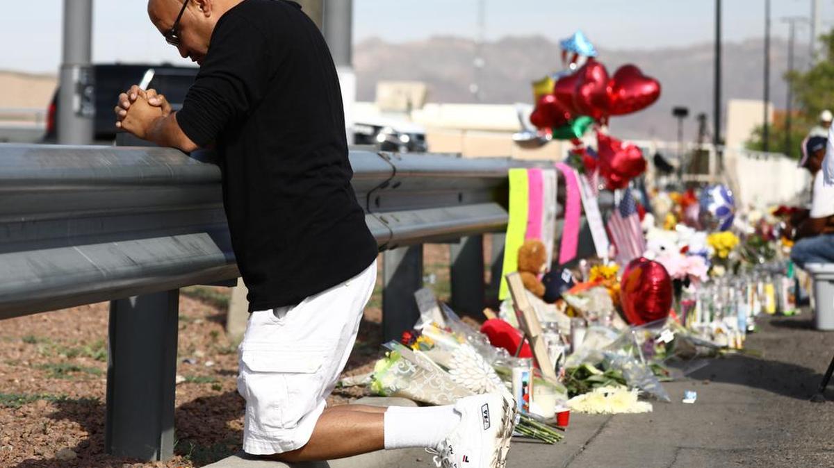 Ángel González reza el lunes junto a flores y velas colocadas en honor a las víctimas de la masacre en Walmart, en El Paso, Texas.