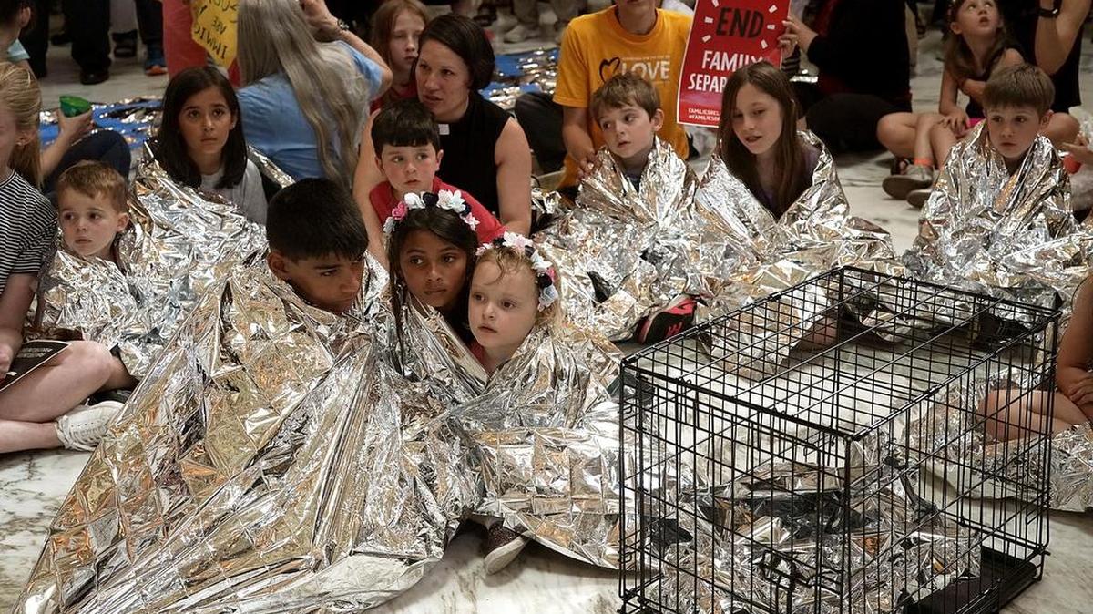 Niños se arropan con mantas isotérmicas para “representar simbólicamente a los miles de niños separados de sus familias en la frontera, durmiendo en pisos y en jaulas”, durante una protesta el 21 de junio en Washington.