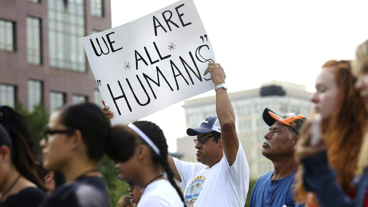 “Somos todos humanos”, dice la pancarta sostenida por Pablo Rodríguez, durante un evento para recordar a las víctimas de las matanzas en El Paso, Texas, y Dayton, Ohio, el domingo 11 de agosto de 2019, en Chattanooga, Tennessee.