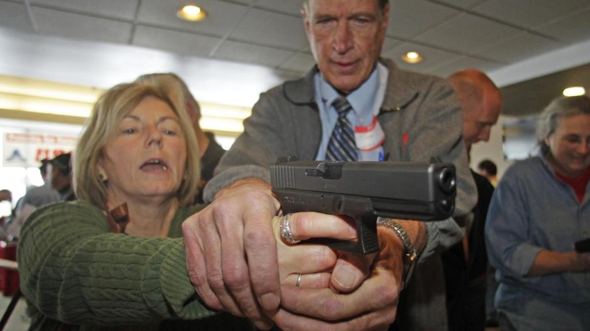 El instructor Jim McCarthy entrena a la maestra Christine Caldwell en el manejo de una pistola Glock de 9 mm en Utah, en el 2012.