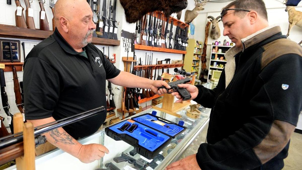 Bill Karnok (izq.), empleado de una casa de empeños en la localidad de Longmont, en Colorado, le muestra una pistola a un cliente.