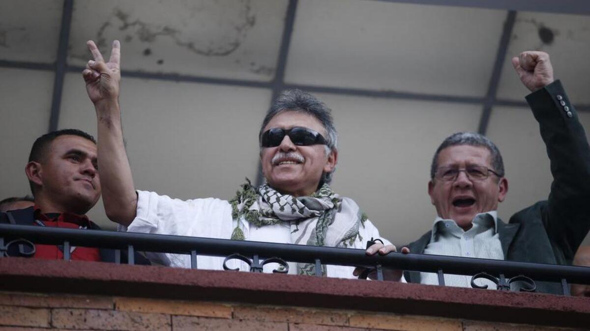 El ex comandante de las FARC, alias Jesús Santrich (centro) saluda desde la sede del partido después que fue liberado, el 30 de mayo en Bogotá. Santrich fue acusado de narcotráfico y posteriormente liberado por la Corte Suprema. A su derecha está Pablo Catatumbo, otro ex comandante guerrillero.