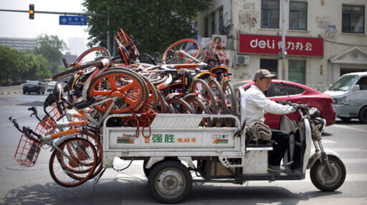 Un trabajador usa un carro eléctrico para transportar bicicletas, por una calle de Pekín, el jueves. Según cifras publicadas el pasado miércoles, la producción industrial y el gasto de los consumidores se debilitó en China como resultado de la guerra de aranceles con Estados Unidos.