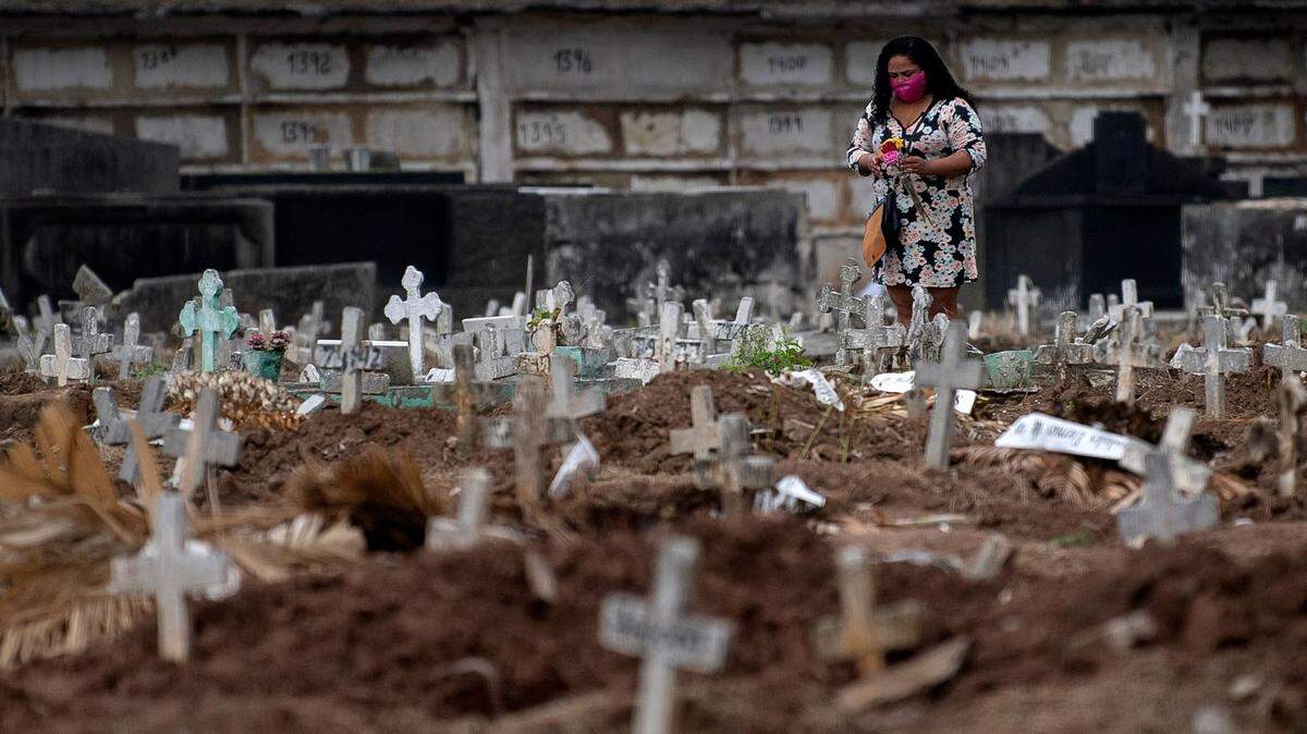(FILES) In this file photo taken on May 8, 2020 a woman visits a relative’s grave at the Caju cemetery in Rio de Janeiro, Brazil, during the COVID-19 coronavirus pandemic. - People are turning to online support groups after losing relatives to COVID-19, the novel coronavirus which has caused 190,000 deaths in Brazil by December 27, 2020. (Photo by MAURO PIMENTEL / AFP) (Photo by MAURO PIMENTEL/AFP via Getty Images)