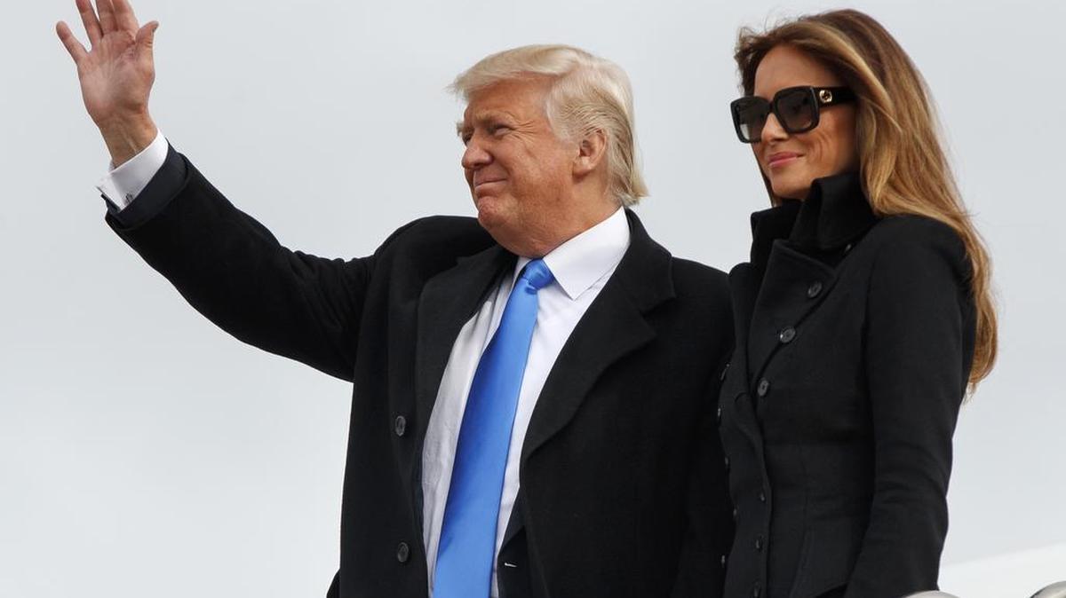 El presidente electo Donald Trump, acompañado por su esposa, Melania Trump, saluda al llegar a la base aérea Andrews, en Maryland, el jueves, un día antes de asumir la presidencia de la nación.