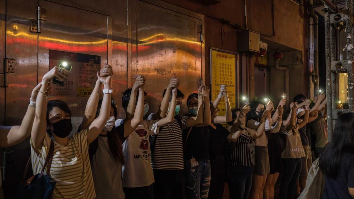 Manifestantes forman una cadena humana iluminada con teléfonos celulares para protestar en contra del gobierno de Hong Kong, el viernes 23 de agosto de 2019 en el vecindario de Kwun Tong.