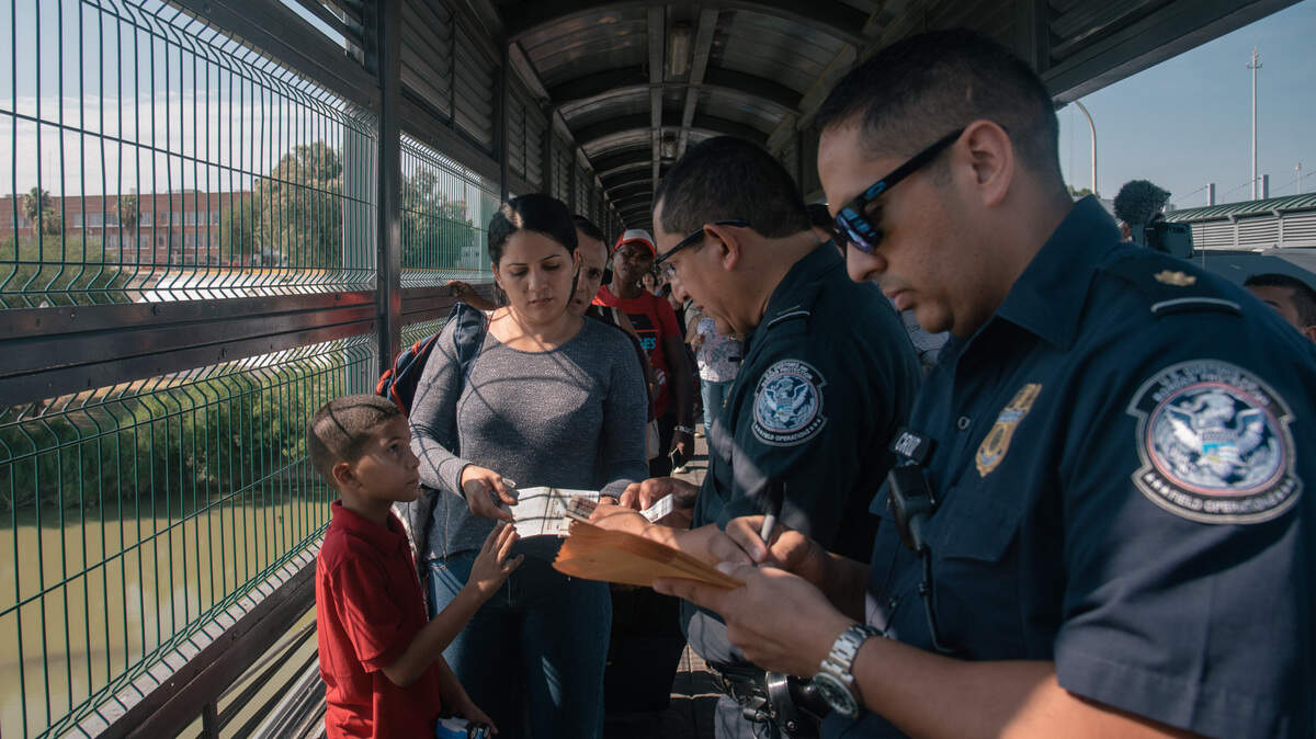 Funcionarios de la Patrulla Fronteriza y Aduanas de EEUU verifican los documentos de una familia venezolana que solicita asilo en el puente internacional entre Laredo, Texas, y Nuevo Laredo, México, el 10 de julio de 2019. La familia esperó durante semanas en Nuevo Laredo, México, conocido por su secuestros y violencia. (Luis Antonio Rojas/The New York Times)