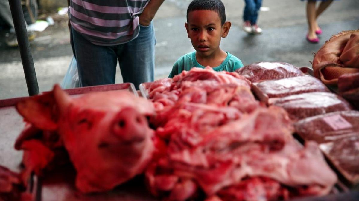 Un niño mira un puesto de carnicería en un mercado callejero en el centro de Caracas, el sábado 21 de octubre del 2017.