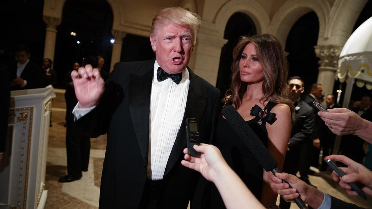 El presidente electo, Donald Trump, junto a su esposa, Melania, habla con reporteros durante una fiesta de víspera de Año Nuevo en su propiedad de Mar-a-Lago, en Palm Beach.