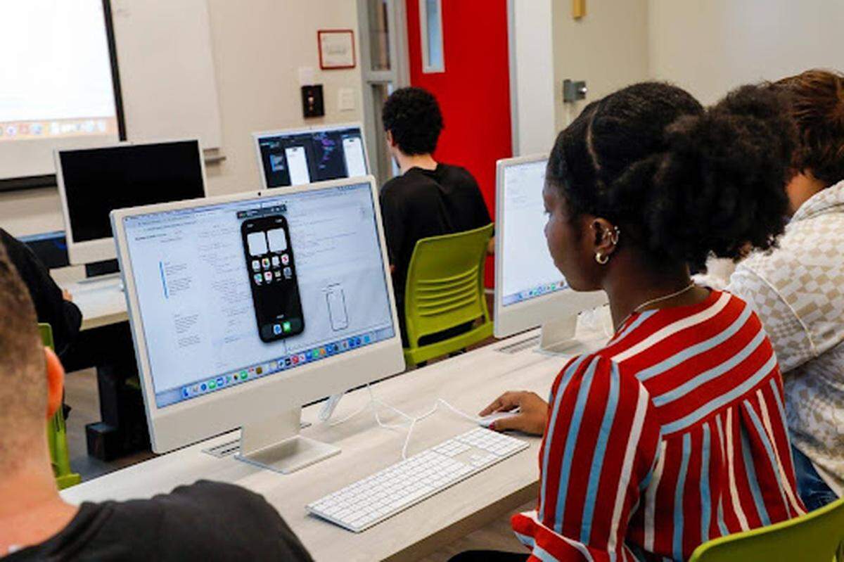 Un instructor ayuda a un estudiante con la programación en Swift en el entorno de aprendizaje práctico de Miami Dade College.