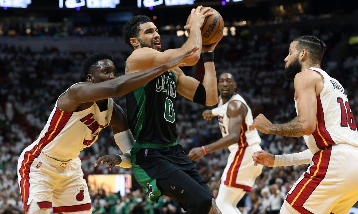 El jugador de los Celitcs Jayson Tatum (centro) entra al aro ante la marca de Victor Oladipo (izq.) y Caleb Martin, del Heat, en el quinto partido de la Final de la Conferencia Este, celebrado el 25 de mayo de 2022 en Miami.
