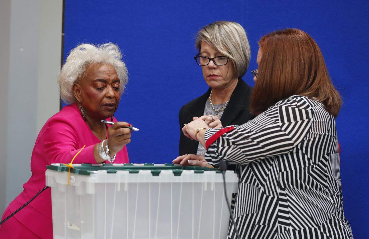 Brenda Snipes (izq), supervisora de Elecciones del Condado Broward, la jueza Betsy Benson (centro), presidenta de la Junta Supervisora, y la jueza Deborah Carpenter-Toye, miembro de la Junta, firman un contenedor sellado para enviarlo al Capitolio estatal antes de comenzar el recuento de boletas, el 12 de noviembre en Lauderhill, Florida.