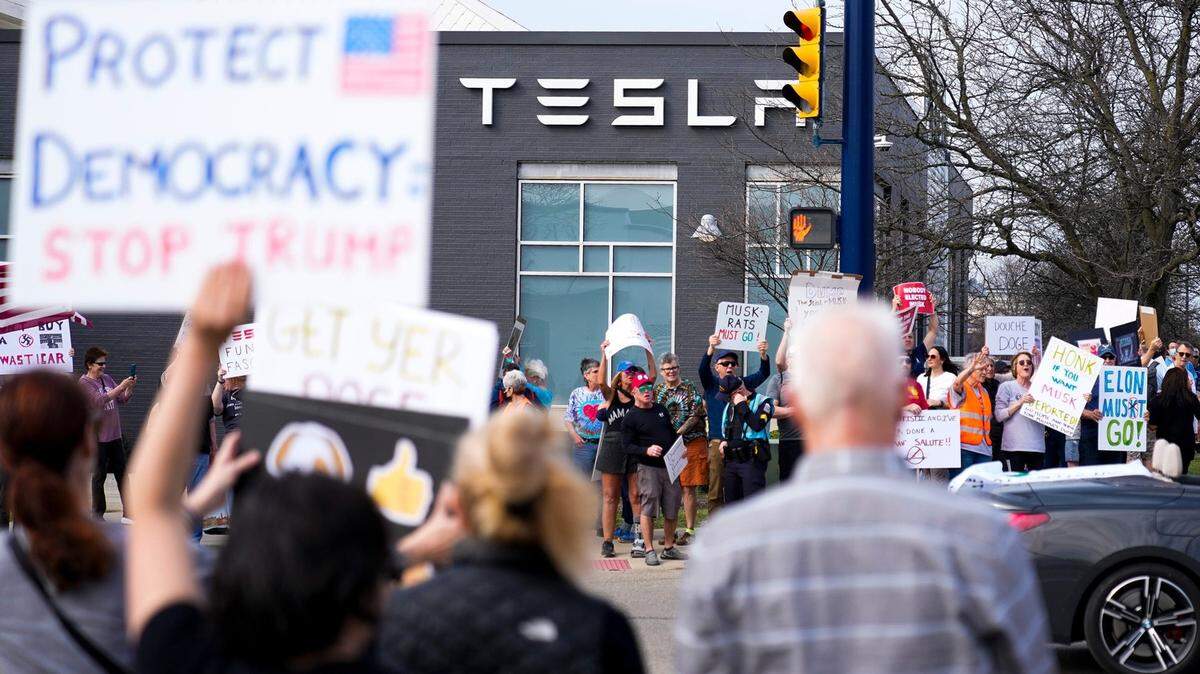 Decenas de manifestantes, una de ellas con una cartel que dice “Protejamos la democracia, detengan a Trump”, protestan frente a un concesionario Tesla en Columbus, Ohio, el sábado 29 de marzo de 2025.