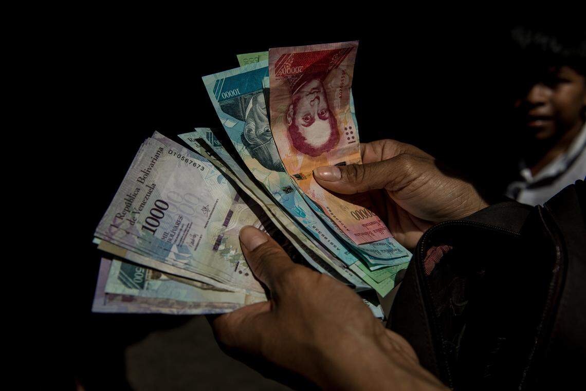 Un hombre cuenta dinero en un mercado en Caracas, Venezuela. Foto de archivo.