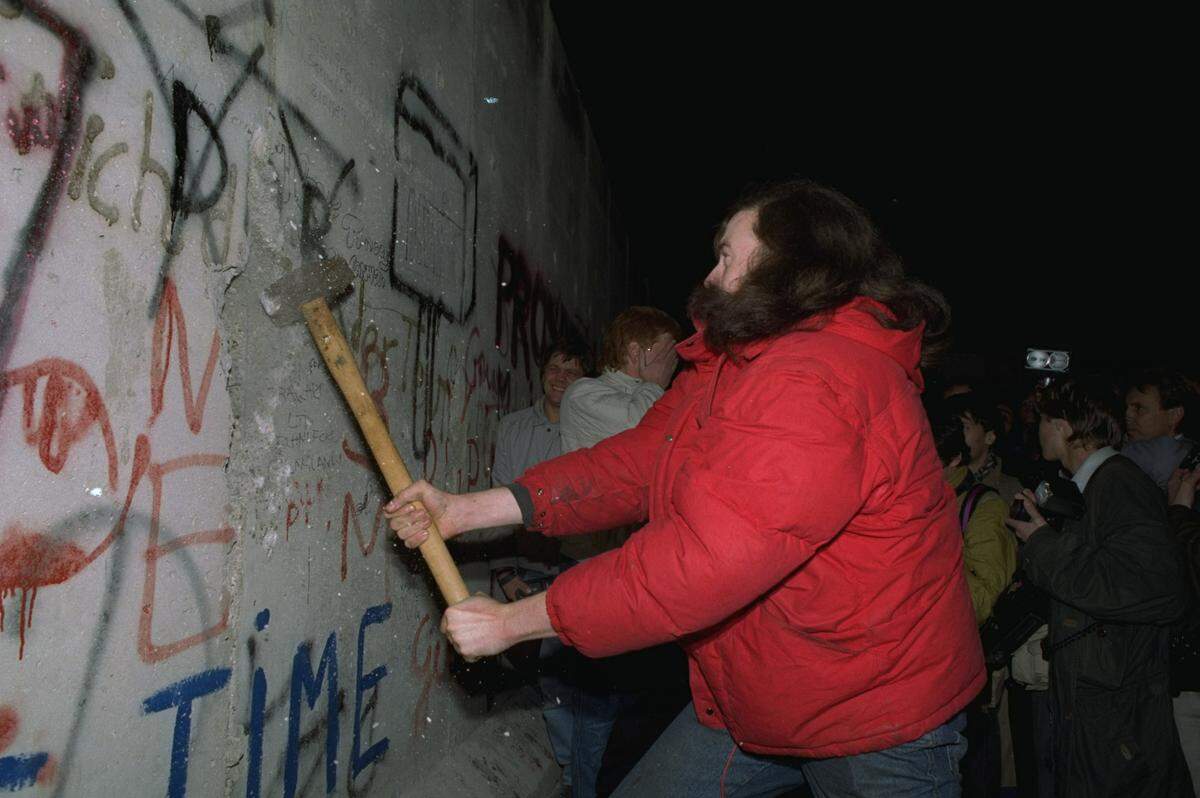 A Berliner tries in vain to demolish a segment of the Berlin Wall with a sledgehammer on November 11, 1989, at Bernauer Strasse, where East German police pulled down segments of the wall for a new passage.