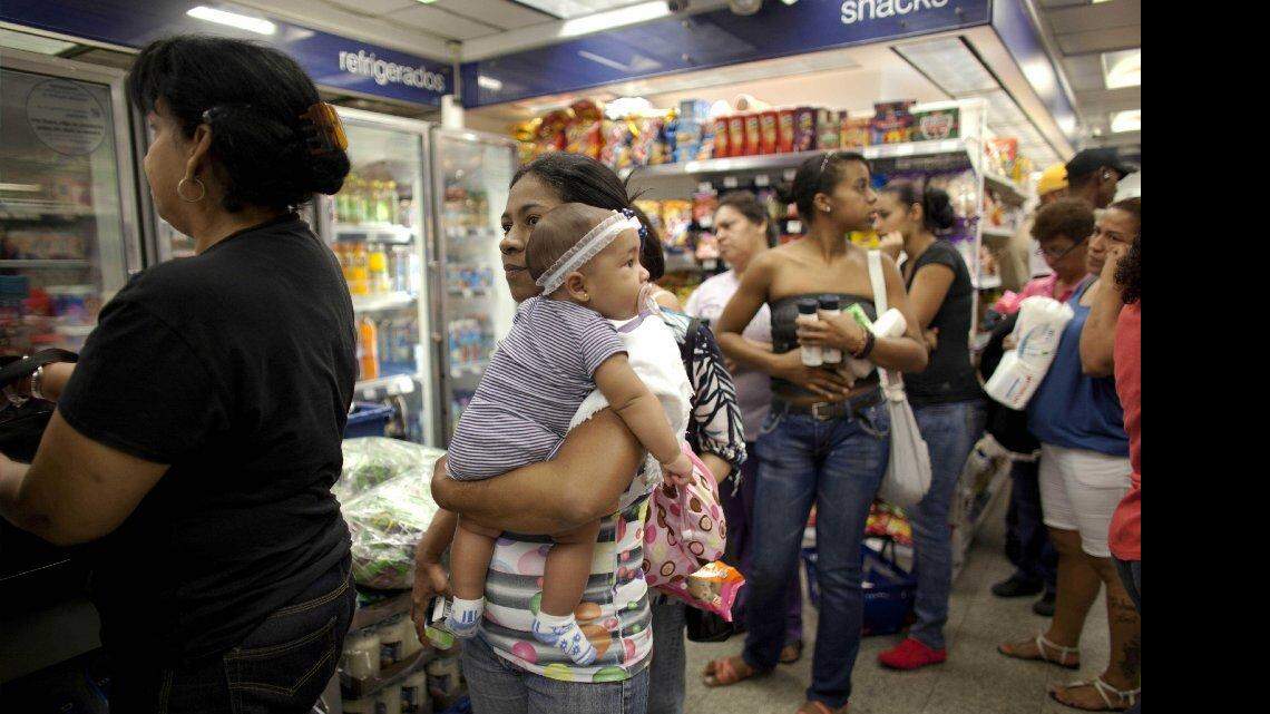 Milagro Álvarez carga a su hija de cinco meses mientras hace fila en una sucursal de la tienda Farmatodo de Caracas, Venezuela, el viernes 24 de octubre de 2014. AP/Archivo