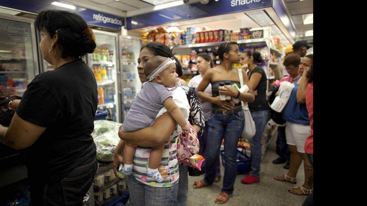 Milagro Álvarez carga a su hija de cinco meses mientras hace fila en una sucursal de la tienda Farmatodo de Caracas, Venezuela, el viernes 24 de octubre de 2014. AP/Archivo