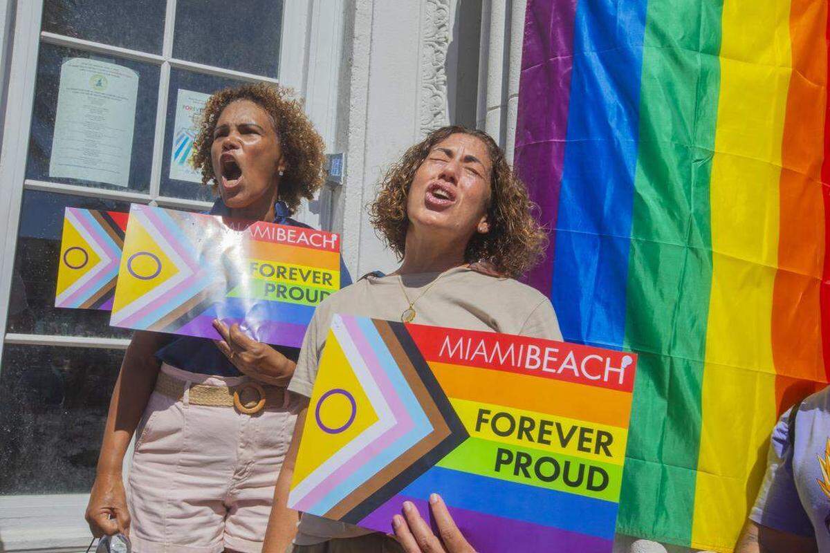 De izquierda a derecha, Salomé Milán y Lilia Tome se congregan junto a otros manifestantes portando banderas arcoíris y carteles con las leyendas “Miami Beach Orgulloso por Siempre” y “No Será Borrado” durante la Marcha Orgulloso por Siempre en Ocean Drive, Miami Beach, Florida, el domingo 31 de agosto de 2025. La marcha se realizó tras la orden de las autoridades estatales de retirar el cruce peatonal del Orgullo LGBTQ de la ciudad.