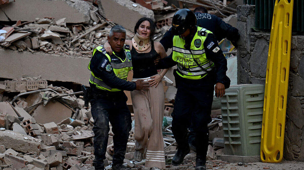 Dos agentes policiales ayudan a evacuar de un edificio a una mujer herida, el miércoles 24 de junio de 2026, en Caracas, Venezuela. Un sismo de magnitud 7.1 sacudió Venezuela el miércoles, según informó el Servicio Geológico de Estados Unidos (USGS).