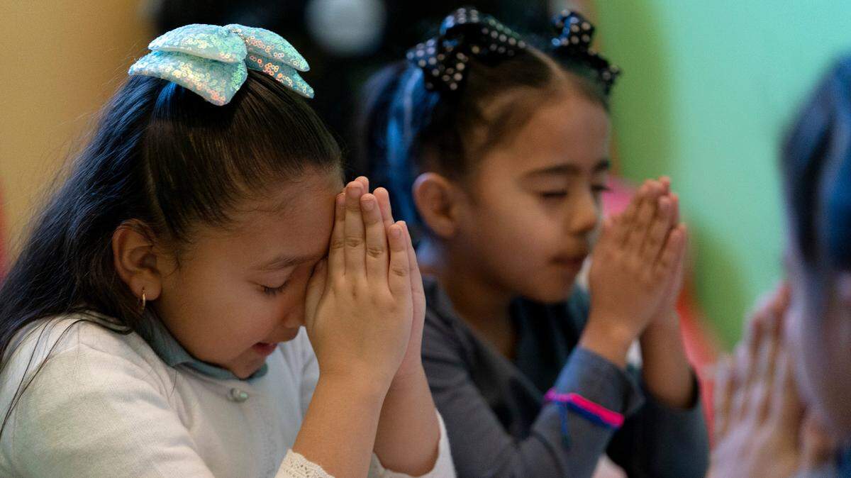 Gaby Meza Rodríguez, de 7 años (izq.), reza con otros niños durante una sesión de escuela dominical mientras sus padres asisten a un servicio religioso, el domingo 17 de diciembre de 2023, en Fort Morgan, Colorado.