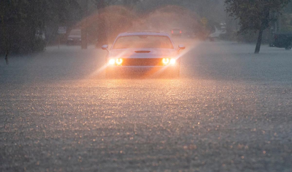 Un conductor enciende las luces de emergencia en Arthur Street en Hollywood, Florida, mientras las fuertes lluvias inundan el vecindario circundante el miércoles 12 de junio de 2024.