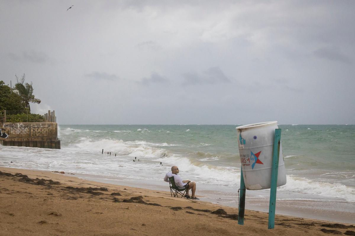 Un hombre se sienta en la playa mientras rompen las olas, antes de la llegada de Fiona en San Juan, Puerto Rico, el sábado 17 de septiembre de 2022. (AP Foto/Alejandro Granadillo)