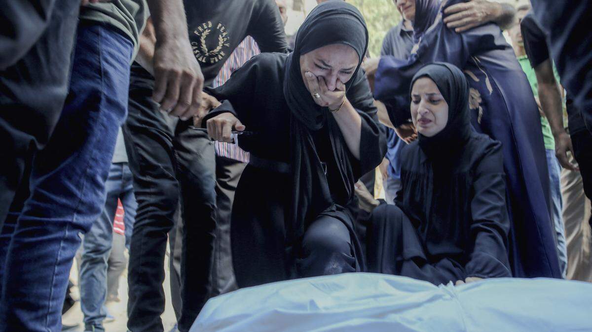 Parientes se reúnen alrededor del cuerpo de un familiar envuelto en un sudario durante un funeral en la ciudad de Gaza, el 7 de agosto de 2025. F