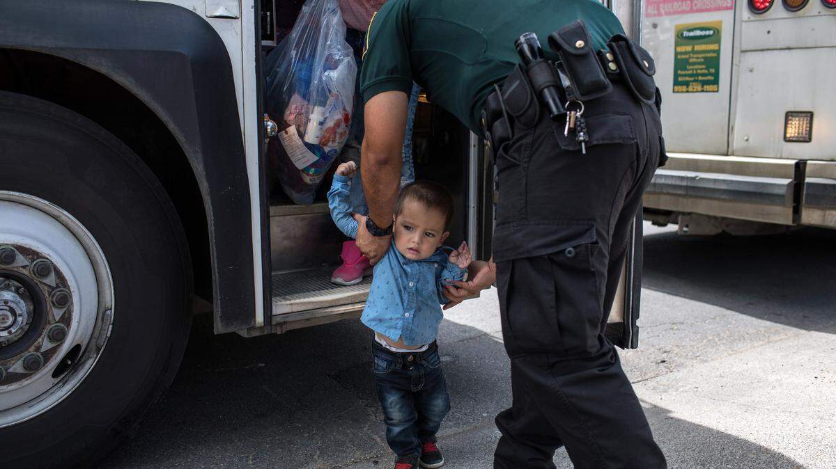 Un agente de CBP ayuda a un niño hondureño de 2 años de edad a bajar de un autobús cuando él y su madre llegaron a una terminal con otros inmigrantes el 24 de junio de 2018 después de ser procesados y liberados en McAllen, Texas.