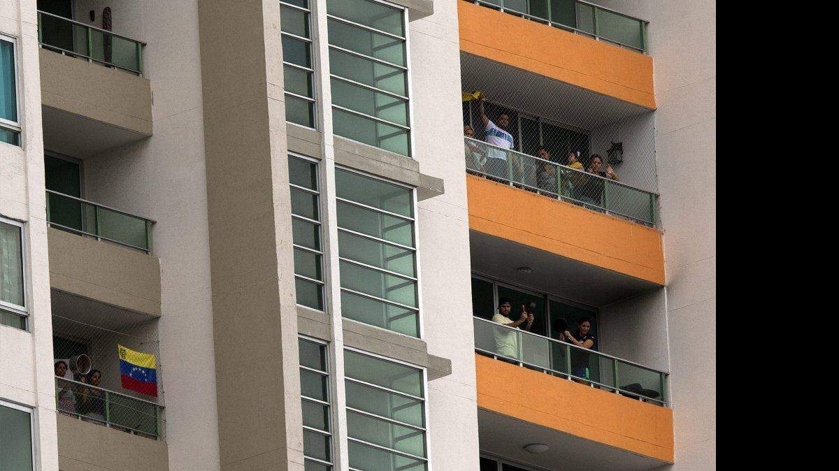 Personas golpean ollas desde los balcones de un edificio, en señal de protesta, mientras el presidente de Venezuela, Nicolás Maduro, pronuncia su discurso en la VII Cumbre de las Américas, en la Ciudad de Panamá, Panamá, el sábado 11 de abril de 2015.