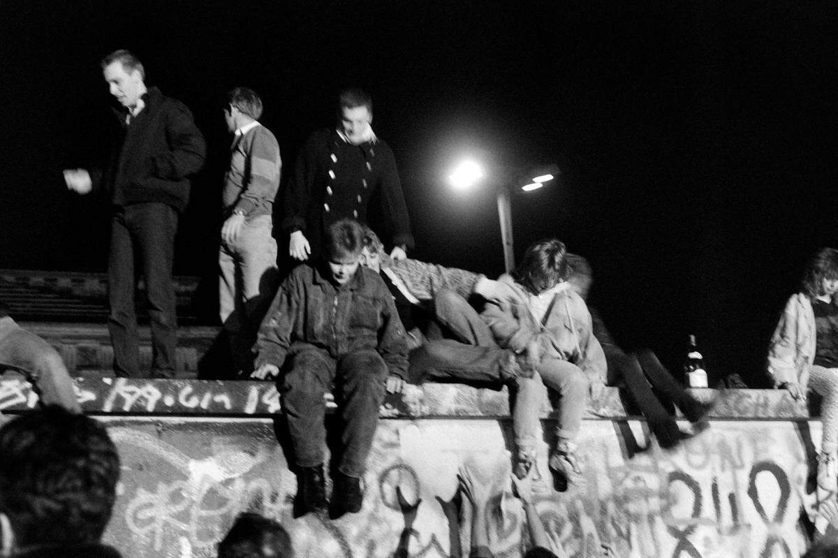 West Berliners climb on the Berlin Wall on November 9, 1989, to ask for its fall. After months of mass protests against the regime and amid a widening exodus of citizens to the West via Hungary, thousands of East Berliners started streaming towards checkpoints leading to West Berlin a few hours after an East German official announced that visas would be freely granted to those wanting to travel outside or leave the state.