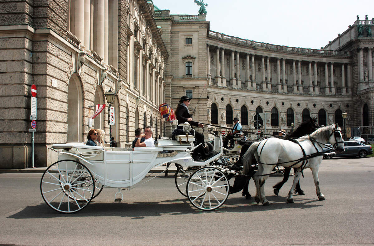 Frente a la Plaza de los Héroes también los turistas pasean en coches tirados por caballos.
