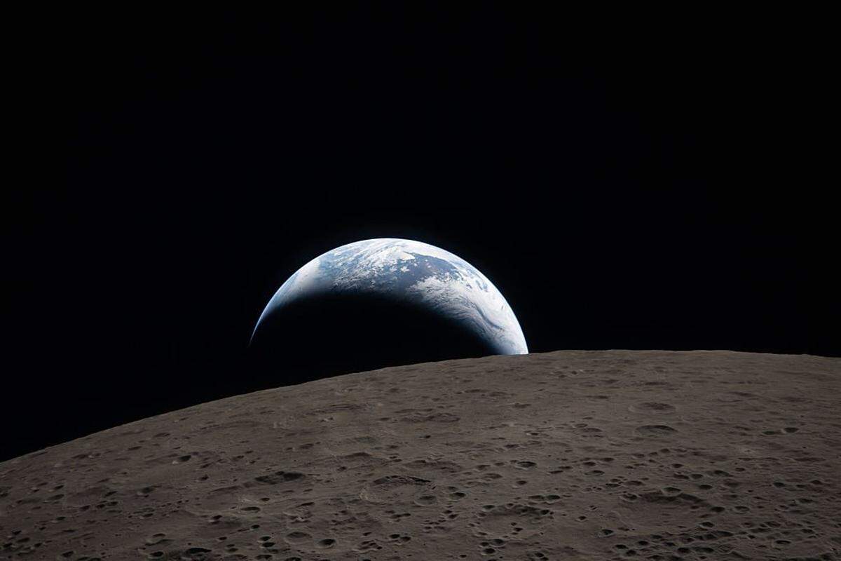 IN SPACE - APRIL 06: (EDITOR'S NOTE: This Handout image was provided by a third-party organization and may not adhere to Getty Images' editorial policy.) In this handout image provided by NASA, Earthset captured through the Orion spacecraft window at 6:41 p.m. EDT, April 6, 2026, during the Artemis II crew's flyby of the Moon. A muted blue Earth with bright white clouds sets behind the cratered lunar surface. The dark portion of Earth is experiencing nighttime. On Earth's day side, swirling clouds are visible over the Australia and Oceania region. In the foreground, Ohm crater has terraced edges and a flat floor interrupted by central peaks. Central peaks form in complex craters when the lunar surface, liquefied on impact, splashes upwards during the crater's formation. (Photo by NASA via Getty Images)