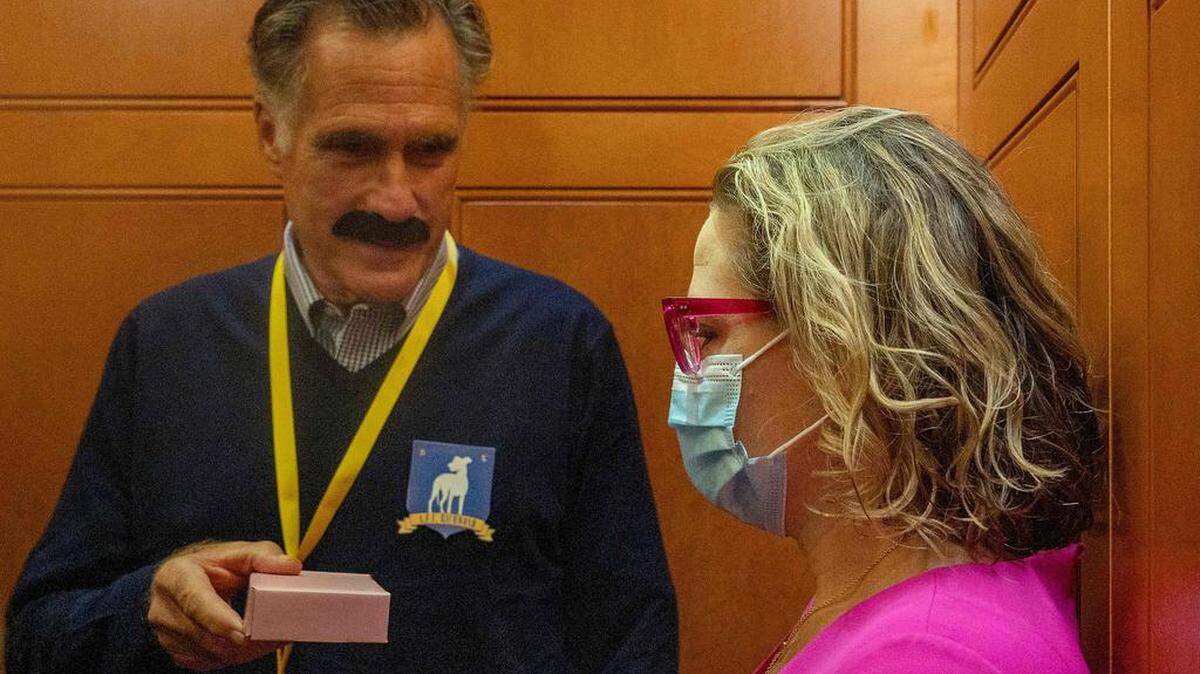 La senadora estadounidense Kyrsten Sinema (R), D-AZ, viaja en el ascensor con el senador estadounidense Mitt Romney (C), R-UT, quien lleva un disfraz de Halloween, en Capitol Hill en Washington, DC el 27 de octubre de 2021.  Jim WATSON / AFP/Getty Images