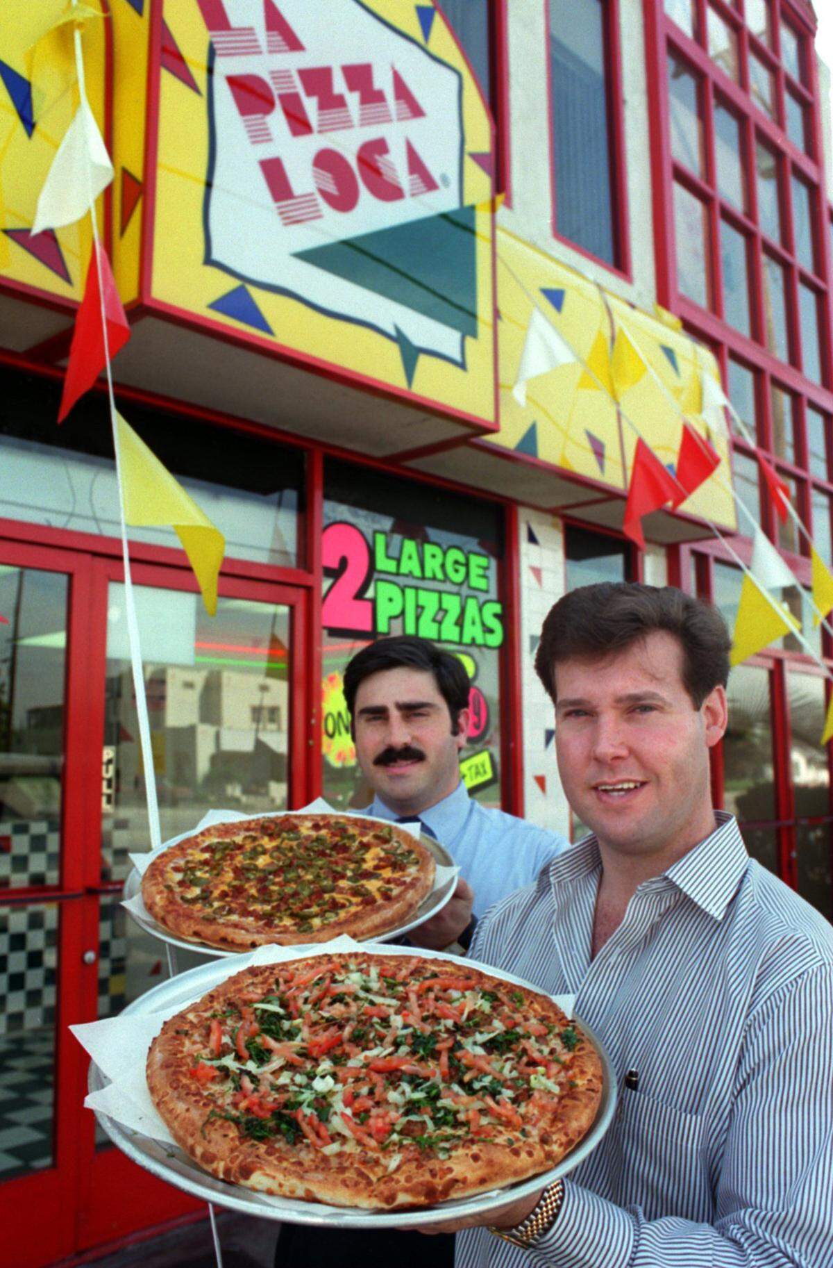 Alex Meruelo (der.) y el ex ejecutivo de La Pizza Loca Tony Tavantzis, frente a la una de las pizzerías en Buena Park en 1995.