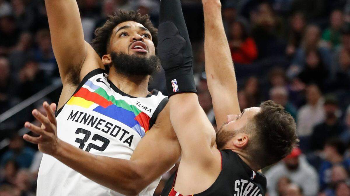 El centro de los Minnesota Timberwolves, Karl-Anthony Towns (32), dispara sobre el escolta de los Miami Heat, Max Strus (31), en el primer cuarto de un partido de la NBA el lunes, 21 de noviembre de 2022, en Minneapolis.