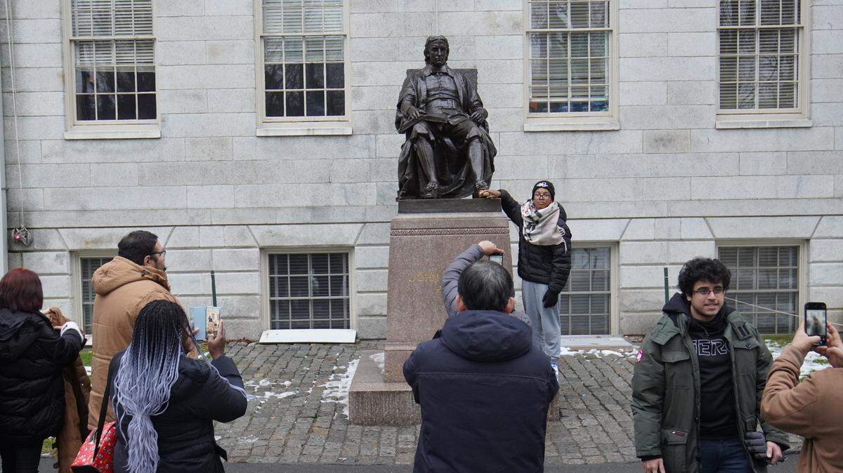 Foto de archivo que muestra a grupo de personas tomando fotos junto a la estatua de John Harvard, el fundador de la prestigiosa universidad, en Boston, Massachusetts, el 28 de diciembre de 2024.
