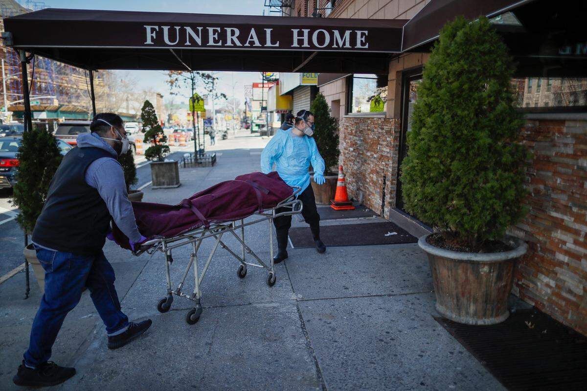 Employees wheel the body of a COVID-19 victim into a Brooklyn funeral home.