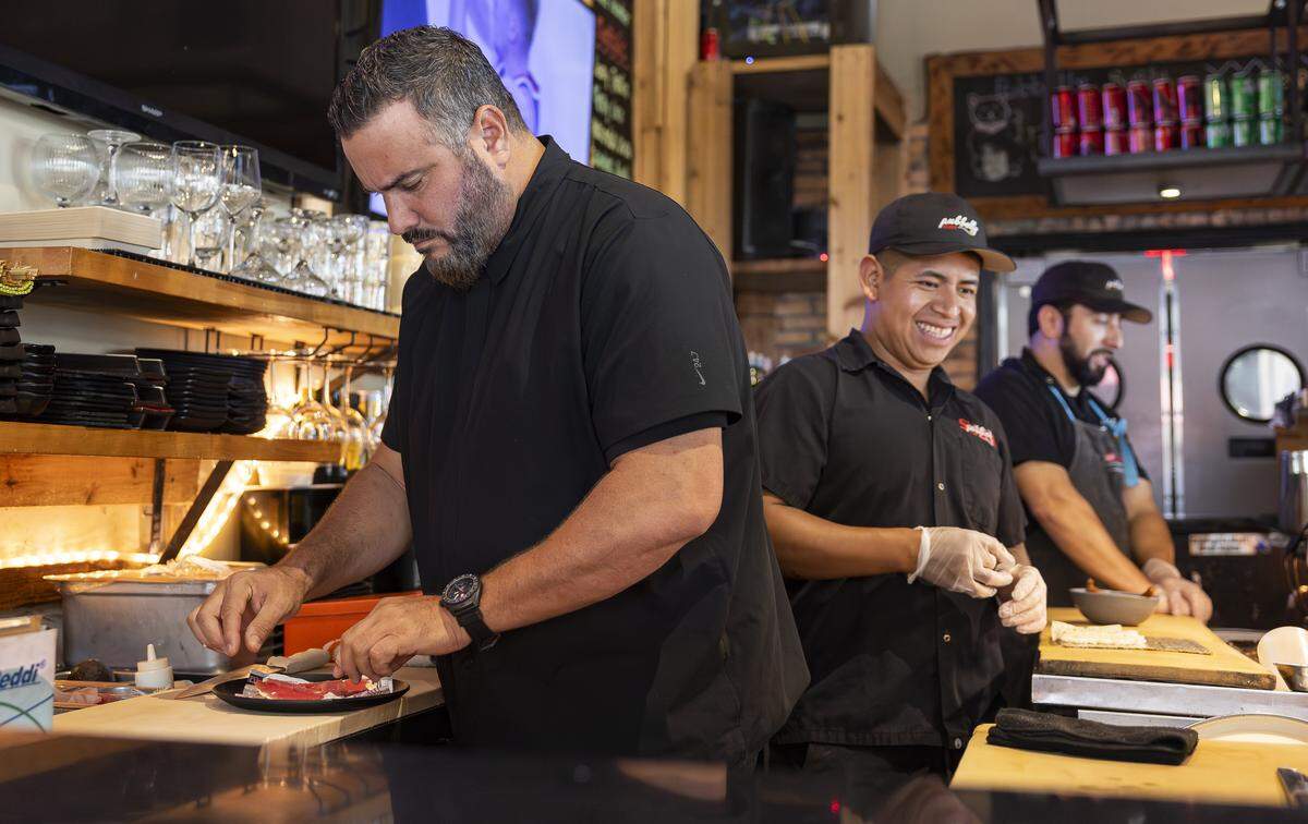 El chef José Mendín (izquierda) prepara una pizza de atún en su restaurante.