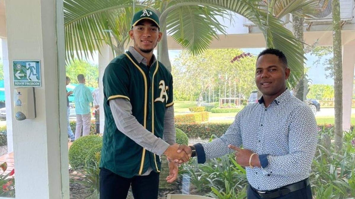 Yunior Tur con el entrenador Yoan Pino durante la firma con los Atléticos de Oakland.