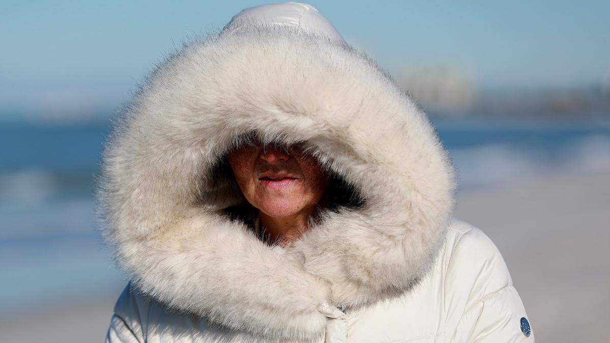 Michelle Foster, de Oklahoma, se abriga contra el clima fresco mientras pasea por la playa el 30 de enero de 2022 en St. Pete Beach, Florida. La temperatura en el centro y norte de Florida descendió durante la noche hasta los 0 °C y -2 °C, pero se espera que suba tras el inicio frío del día.