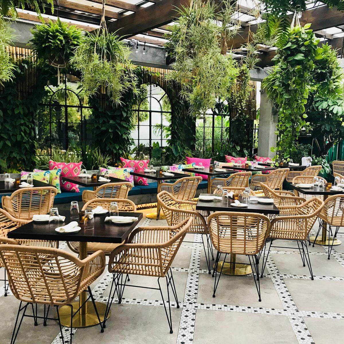 Un acogedor patio al aire libre cubierto con una decoración relajada, plantas tropicales y acabados de bambú se asemeja a la tierra natal de Blanco en Costa Rica.