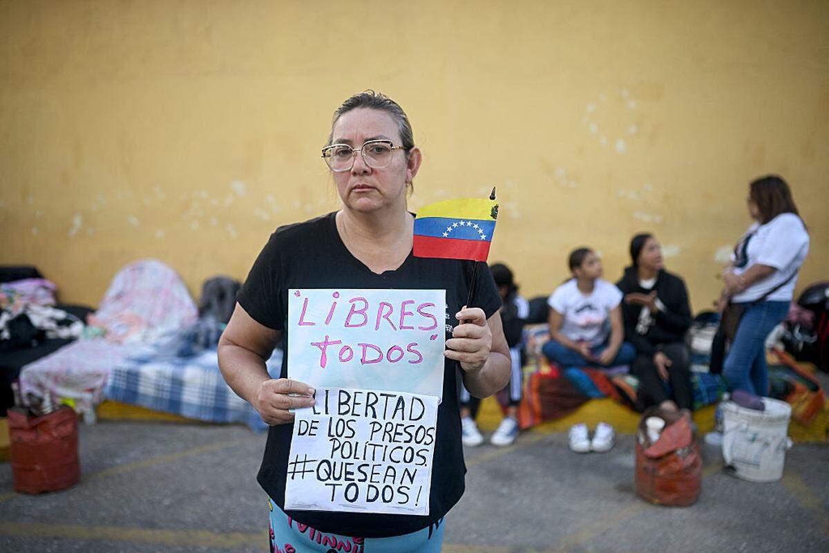 Evelis Cano, madre de Jack Tantak Cano, quien se encuentra encarcelado, sostiene un cartel que exige la libertad de todos los presos políticos frente a la Zona 7 de la Policía Nacional Bolivariana (PNB) —también conocida como Centro de Control y Custodia de Detenidos de Boleíta— en el municipio Sucre, Distrito Metropolitano de Caracas (DMC), Venezuela, el domingo 11 de enero de 2026.