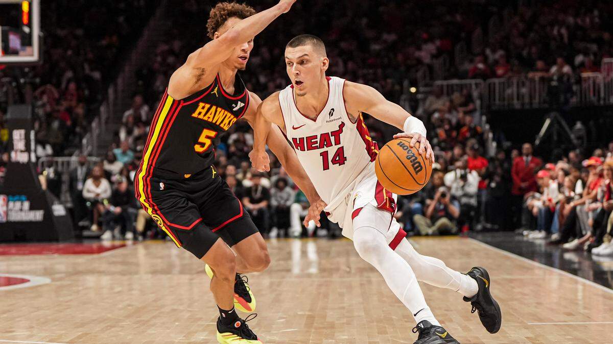 El escolta del Miami Heat, Tyler Herro (14), avanza ante el escolta de los Atlanta Hawks, Dyson Daniels (5), durante la segunda mitad en el State Farm Arena, el 18 de abril de 2025, en Atlanta, Georgia.