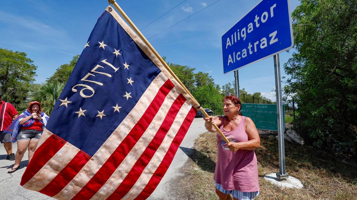 Rena Mourer, quien está a favor de Alligator Alcatraz, agita una bandera estadounidense de Betsy Ross de 1776 en la entrada principal de Alligator Alcatraz mientras legisladores de Florida y miembros del Congreso recorren la instalación de detención ubicada dentro de los Everglades de Florida, a 36 millas al oeste del distrito comercial central de Miami, en el condado de Collier, Florida, el sábado 12 de julio de 2025.