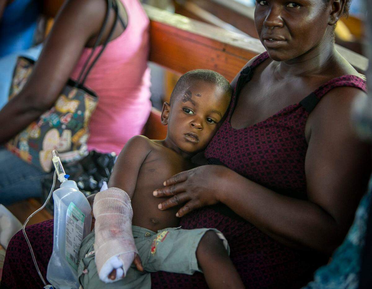 Les Cayes, Haiti, August 16 2021 - A young boy  who was injured during the earthquake is comforted by his mother at Center De Sante Lumiere hospital in Les Cayes. Many people injured during the earthquake are being taken to the airport so the U.S. Coast Guard can fly them to Port-au-Prince.