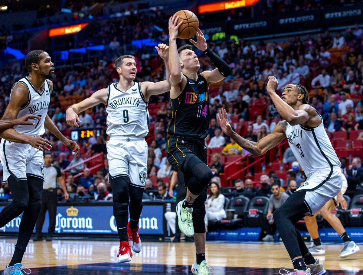 El escolta del Heat Tyler Herro (der.) tira al aro ante la defensa de los Nets de Brooklyn, en el partido celebrado el 26 de marzo de 2022 en Miami.