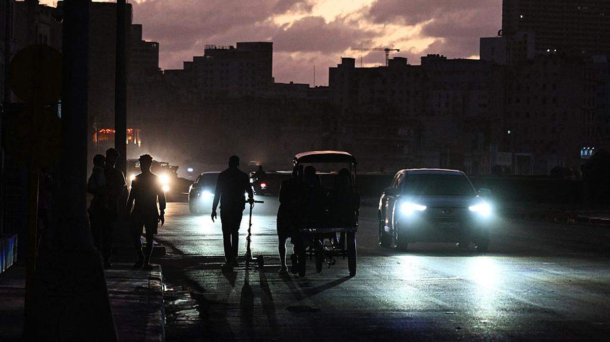 Personas transitan por una calle durante un apagón nacional en La Habana, Cuba, el 21 de marzo de 2026. 