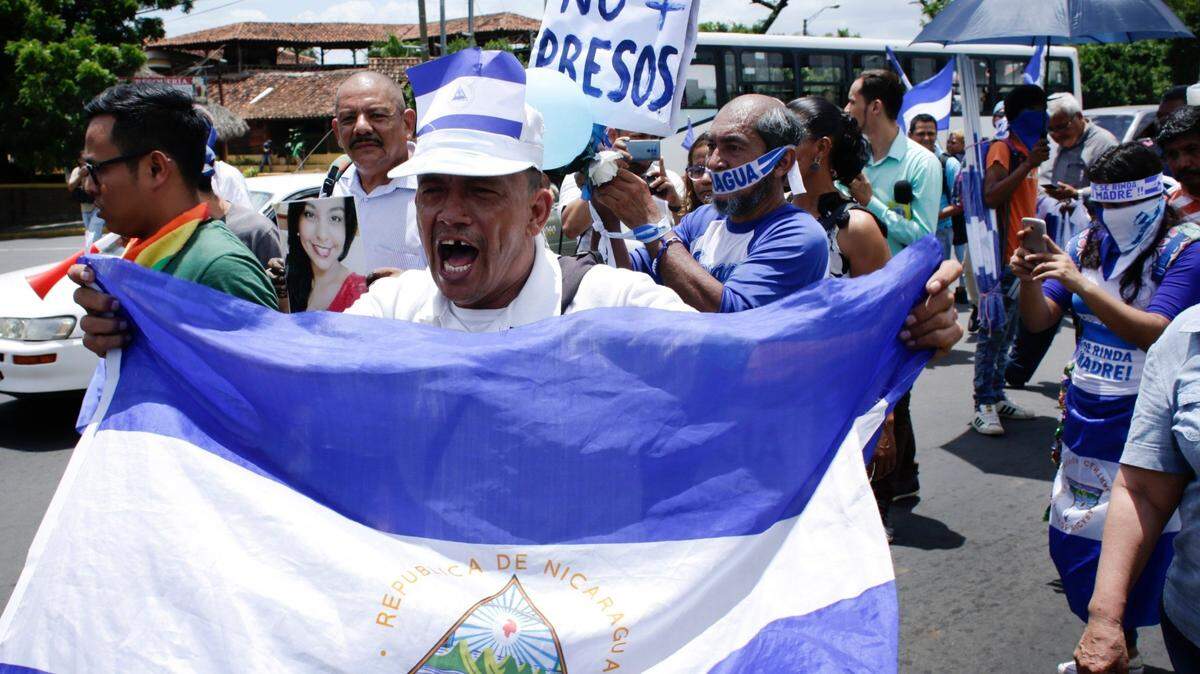 Un hombre con una bandera nacional nicaragüense grita consignas antigubernamentales durante una protesta para apoyar a los periodistas recientemente atacados mientras cubrían las protestas que exigían la renuncia del presidente Daniel Ortega y la liberación de todos los presos políticos en Managua, Nicaragua, el lunes 30 de julio de 2018. (Foto AP / Arnulfo Franco)