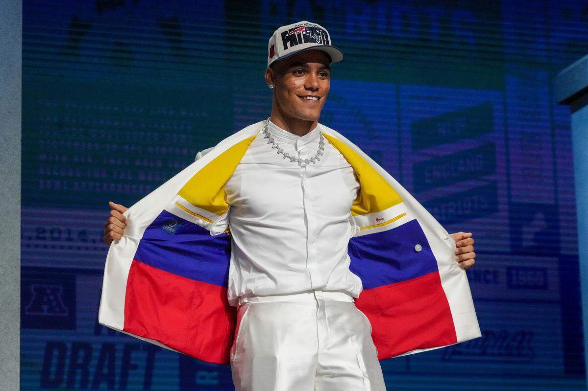 El cornerback Christian González se abrió la chaqueta blanca para dejar ver el forro decorado con los colores de la bandera colombiana, luego de ser reclutado en el Draft de la NFL, el 27 de abril de 2023 en Kansas City. 