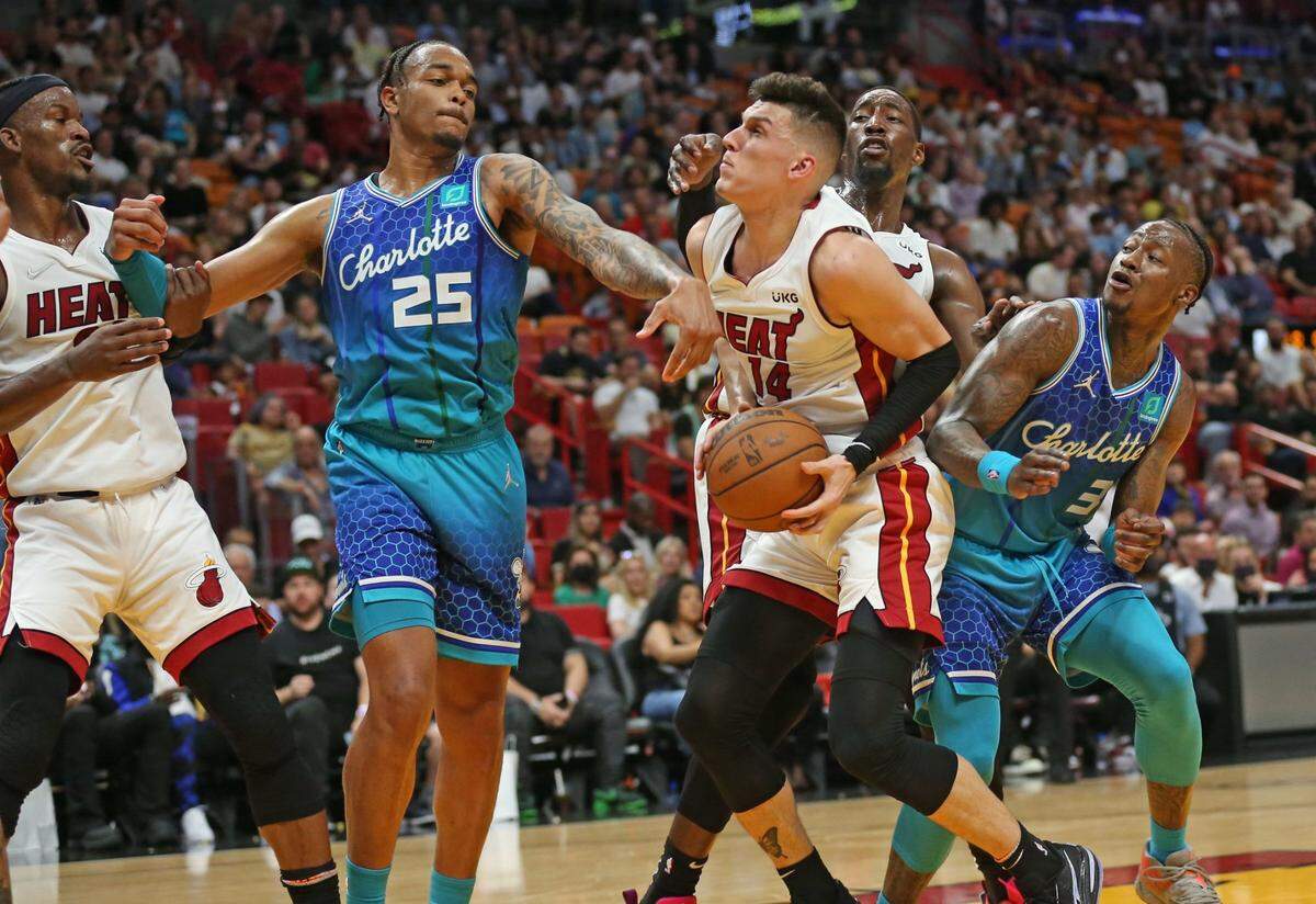 El jugador del Heat Tyler Herro (centro) entra al aro ante la marca de P.J. Washington, de los Hornets de Charlotte, en el partido celebrado el 5 de abril de 2022 en Miami.